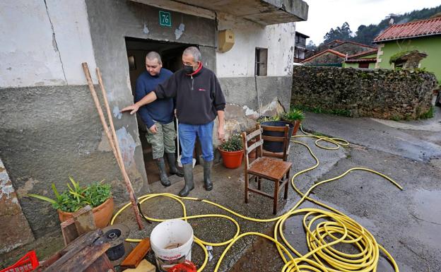 Vecinos de Molleda limpiando el barro de sus casas, esta mañana.