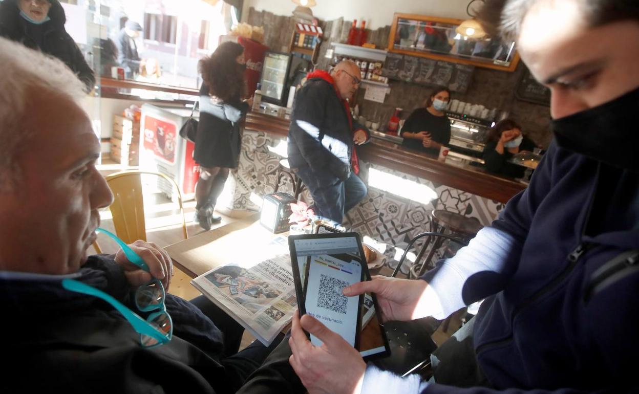 Un cliente muestra su pasaporte covid en un bar de Barcelona.