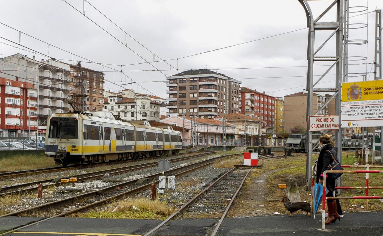 Un tren circula por el paso a nivel de la calle Pablo Garnica, con la estación de Feve de Torrelavega al fondo.