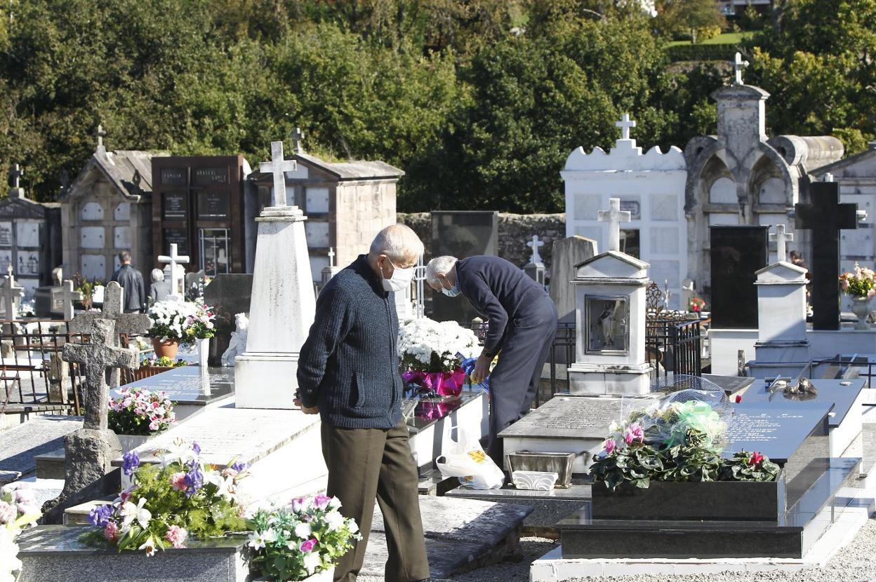 Dos hombres visitan el cementerio de Geloria, en La Llama, durante la reciente festividad del Día de Todos los Santos.