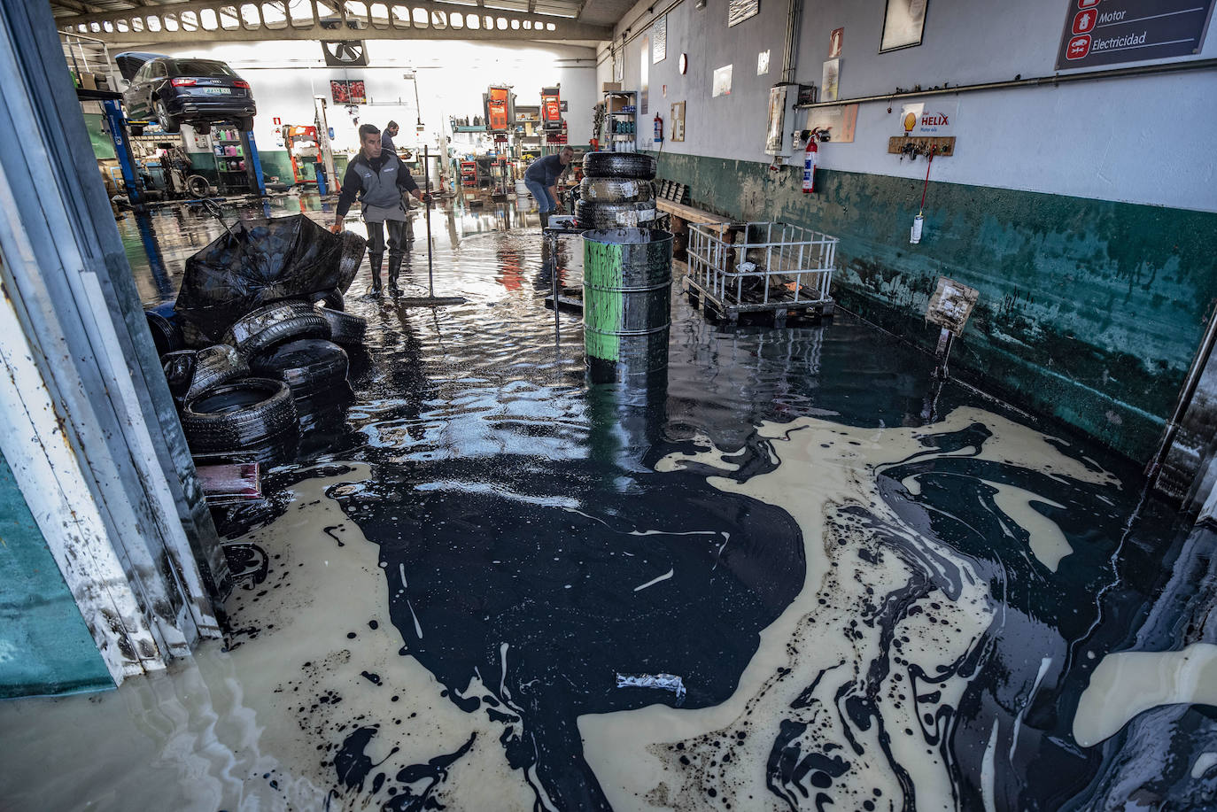 El aceite del los coches y el agua se mezclan todavía en el taller.