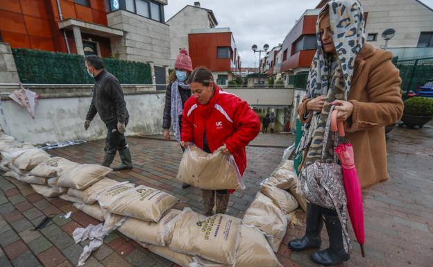 Imagen. Los vecinos de Oruña ponen sacos para intentar que no entre más agua a sus garajes. 