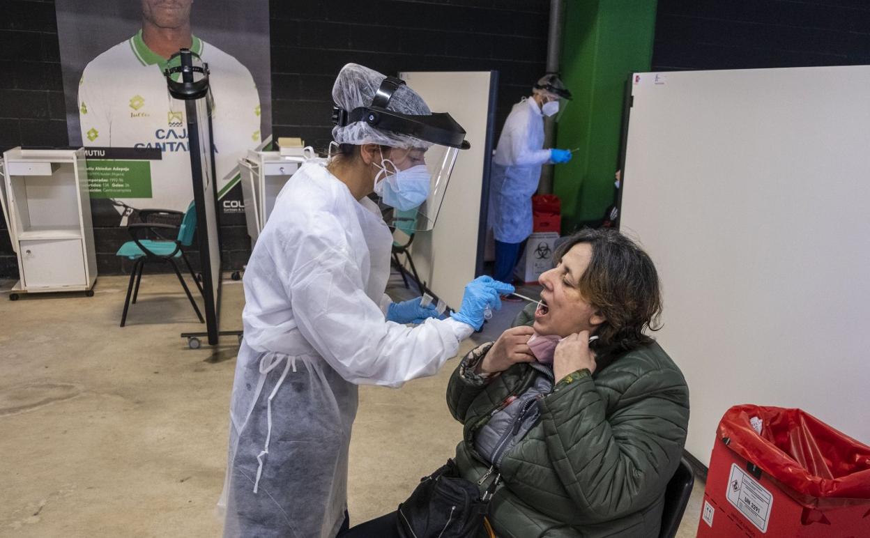 Una sanitaria toma la muestra de saliva para la prueba PCR a una mujer en el punto de recogida de los Campos de Sport de El Sardinero. 