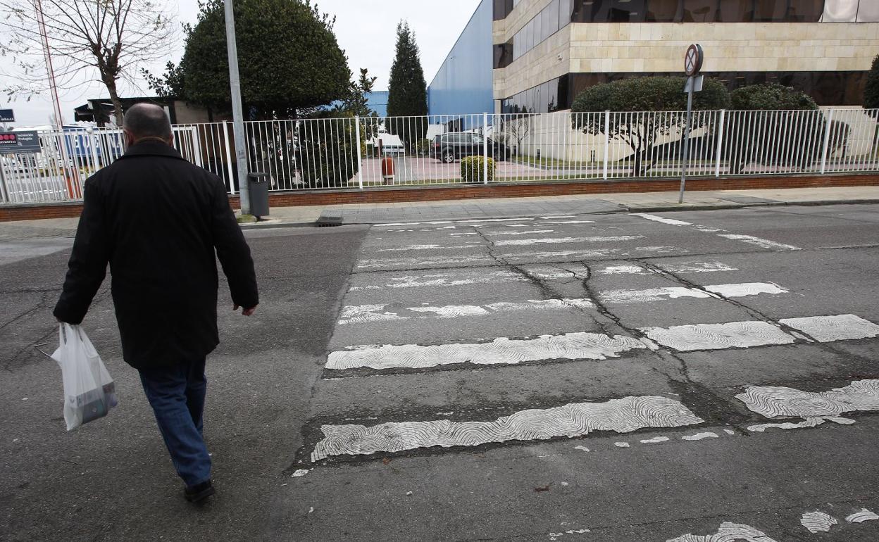 Un hombre cruza por un paso de peatones, en el que apenas se aprecia la pintura blanca, en la calle Pablo Garnica