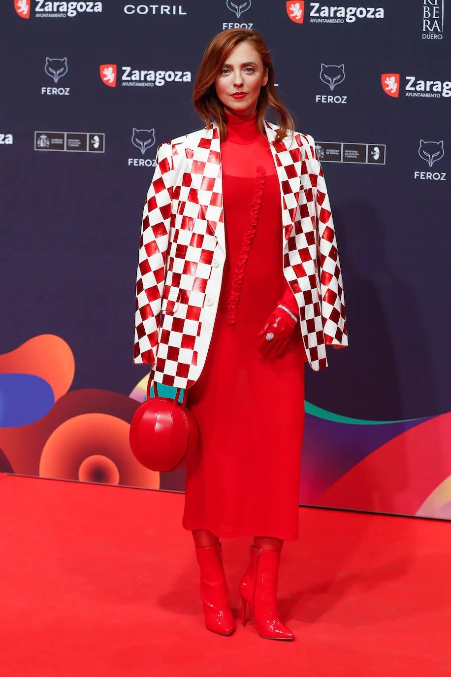 Leticia Dolera. La polifacética actriz lució uno de los pocos looks con color y estampado de toda la alfombra roja. Combinó esta ‘blazer’ con ‘print’ damero con un vestido, botas y bolso todo en tonos rojos. Un diseño firmado por Maison Margiela. 