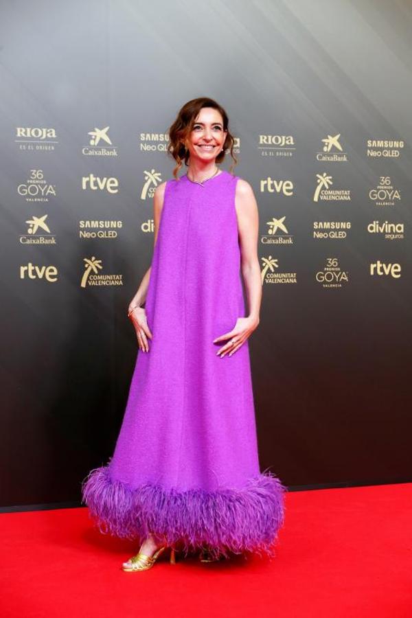 La directora de cine Paula Palacios apuesta por el color de moda de este año, el bautizado por Pantone como "Very Peri". Ha elegido un vestido con una silueta limpia y minimal, rematada con plumas en el bajo. Lo ha combinado con sandalias de tiras doradas de Lodi.