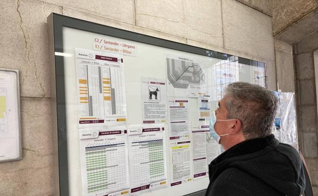 Un hombre consulta el panel con los horarios en la estación de Santander.