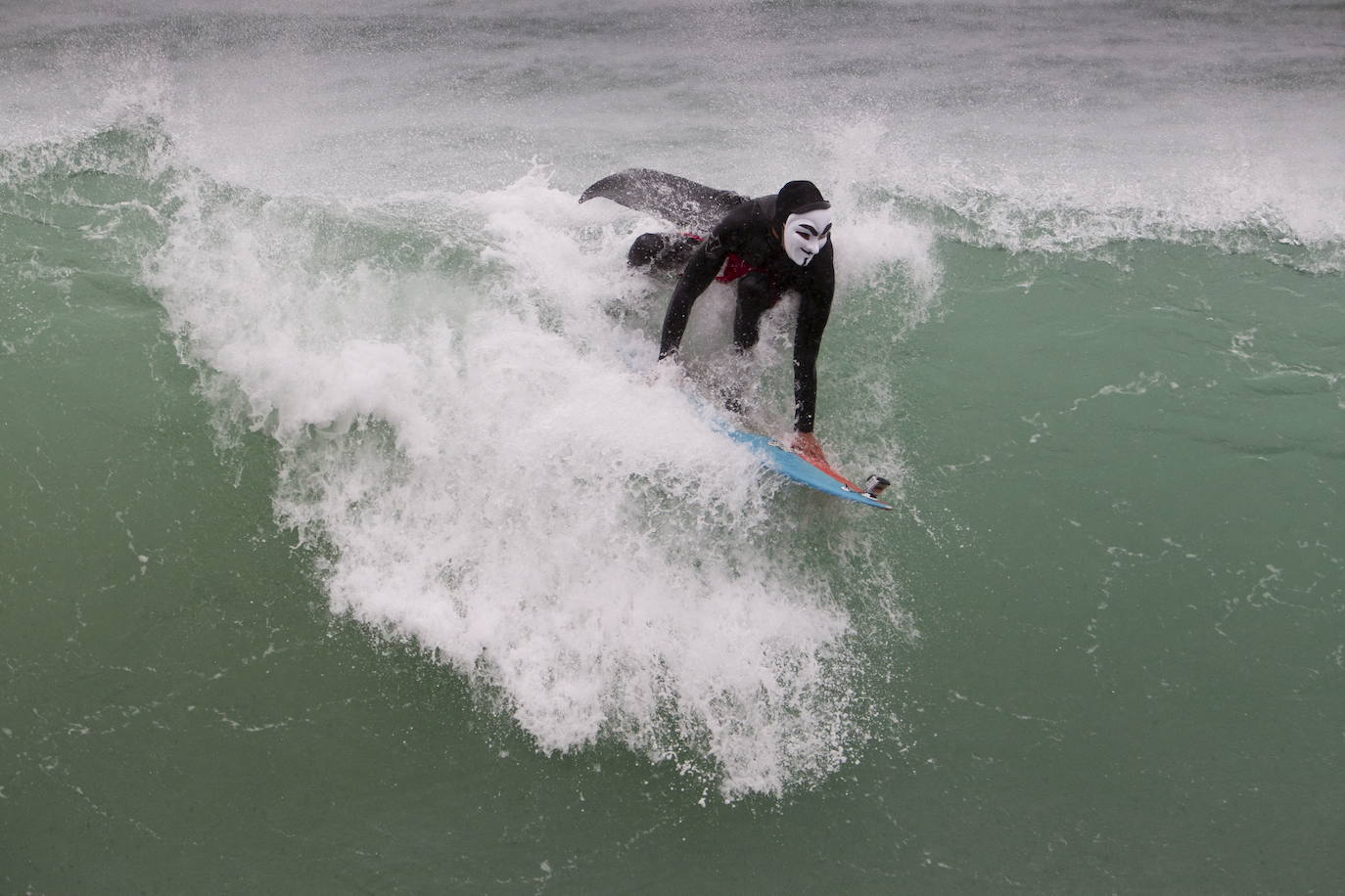 Surfista cogiendo olas en El Sardinero con la careta de anonymous en 2014 