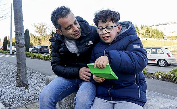 Rafael Álvarez posa junto a su hijo Arón, que se divierte con una consola.