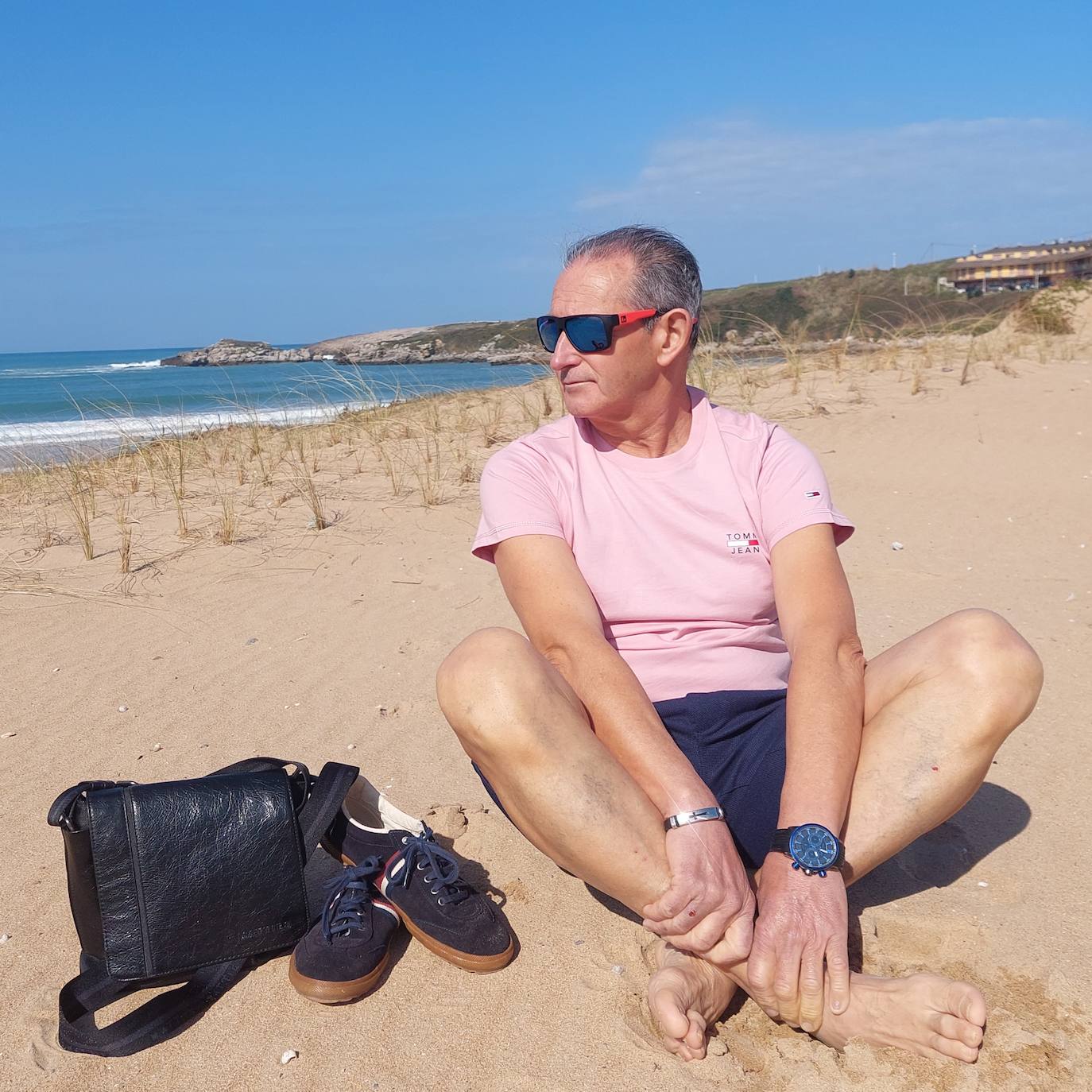 Foto 'casual' con camiseta de manga corta de Tommy Jeans, bermudas en azul, todo combinado con los complementos: gafas de sol, deportivas y bolso.