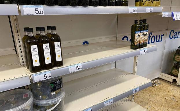 Imagen principal - Imagen de estanterías de aceite y pasta y harina semivacías en el Carrefour de Peñacastillo, este sábado.