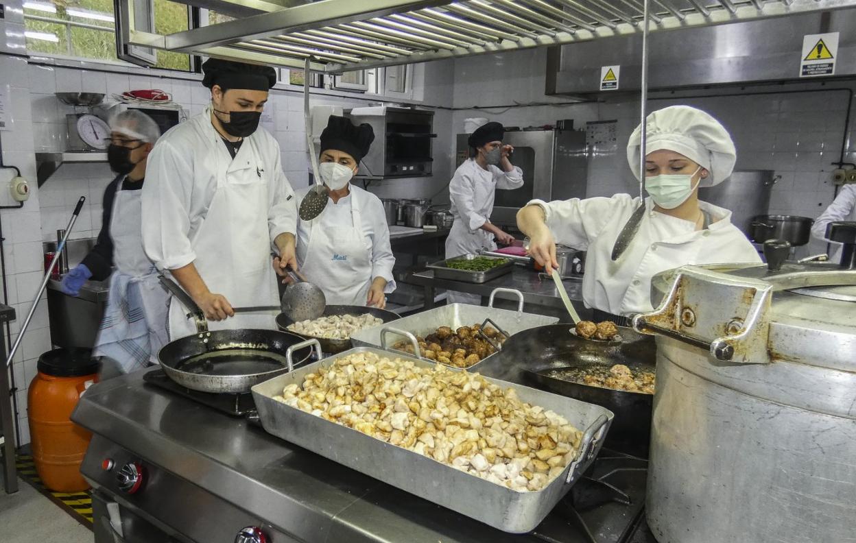 Varios alumnos preparan uno de los platos diseñados para el menú solidario