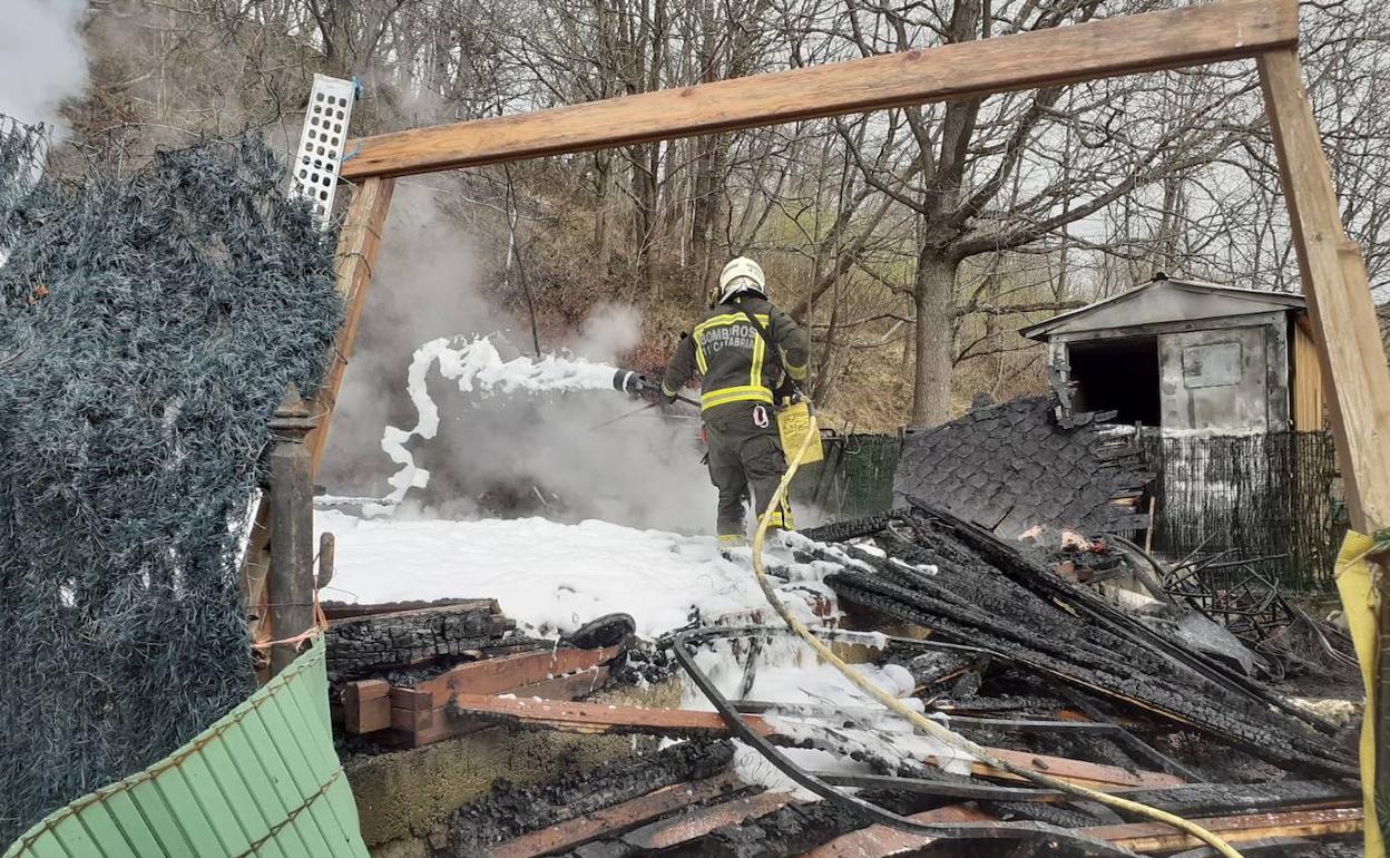 Un efectivo de los bomberos cubre con un colchón de espuma la estructura para evitar que puntos caliente ocultos puedan reavivar el fuego. 