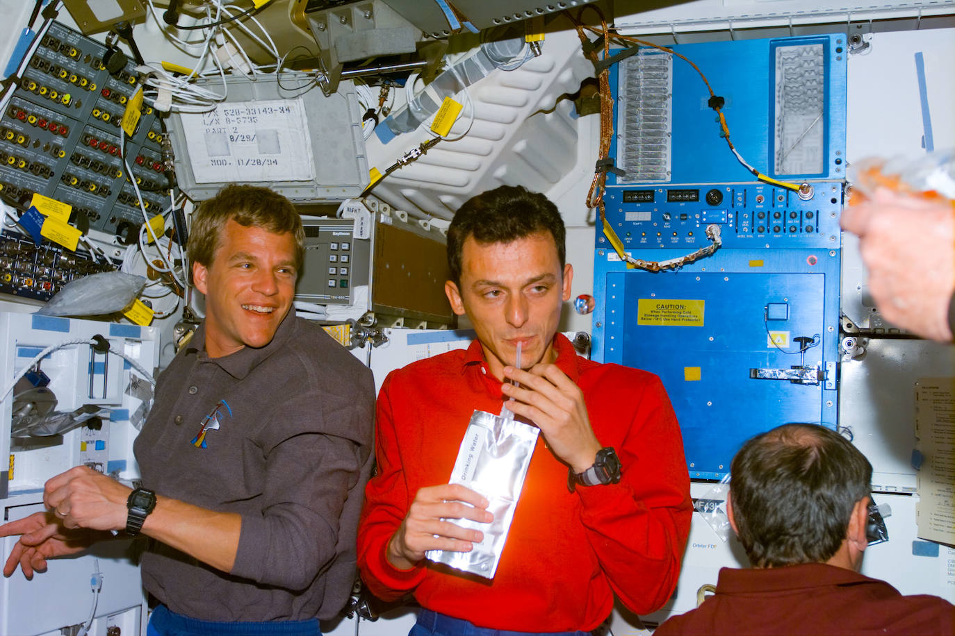 El astronauta español Pedro Duque bebe agua junto a Scott F. Parazynski durante una misión del transbordador Discovery en 1998.