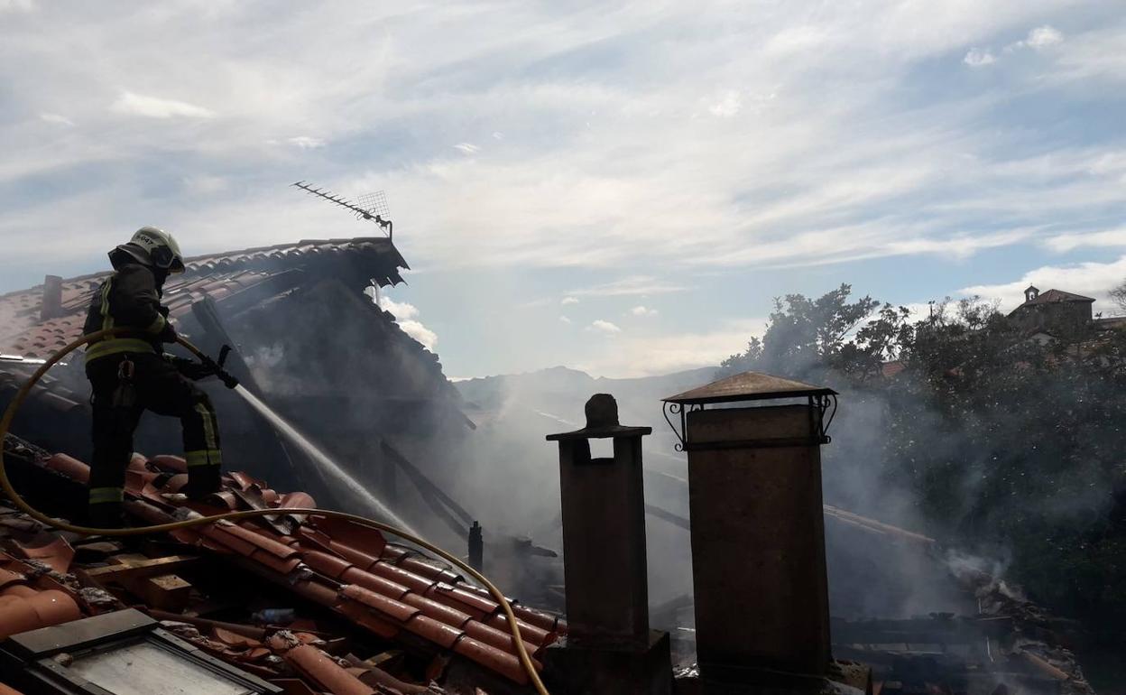 Imagen de un bombero en el tejado de la casa, mientras trataba de apagar el fuego.