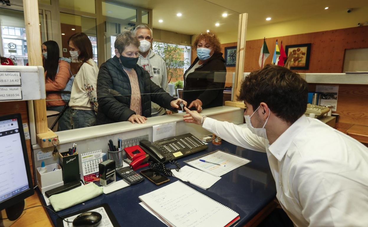 Lidiya, junto a su marido Serhiy y Olena, entrega las llaves de su habitación en el mostrador del hotel donde residen bajo la tutela de Cruz Roja Cantabria. Detrás, Olha ante el carrito de bebé de otra ucraniana. 