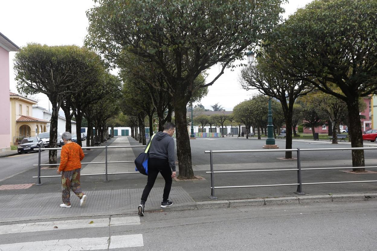 Dos vecinos del barrio San Gil caminan por la plaza, que tiene árboles en su perímetro.