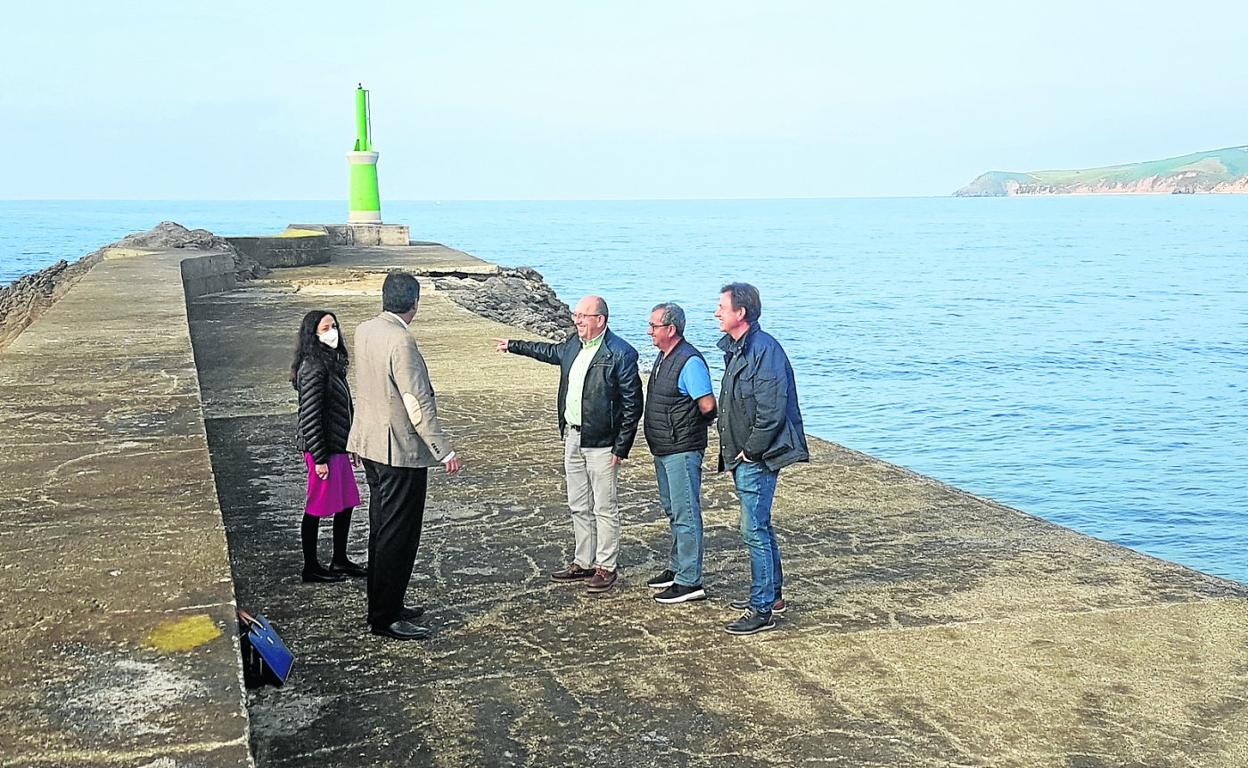 El consejero, junto al patrón mayor y el alcalde, en el extremo del espigón contemplando la zona en la que se realizará el dragado en roca. 