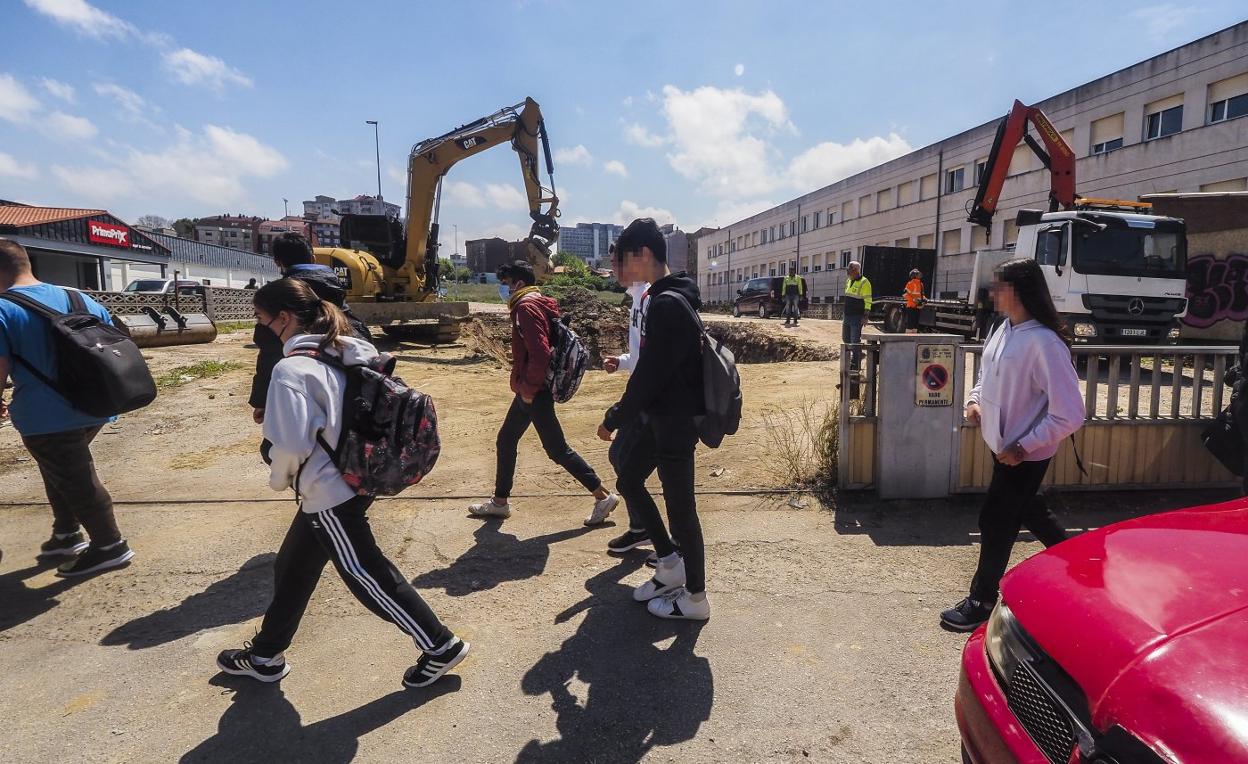 Alumnos del IES Cantabria pasan junto a las obras de la gasolinera.