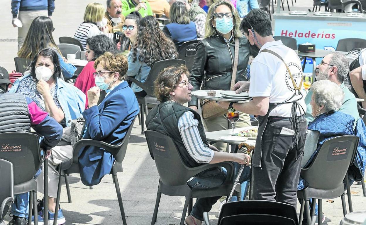 Un camarero atiende una mesa en una terraza. 