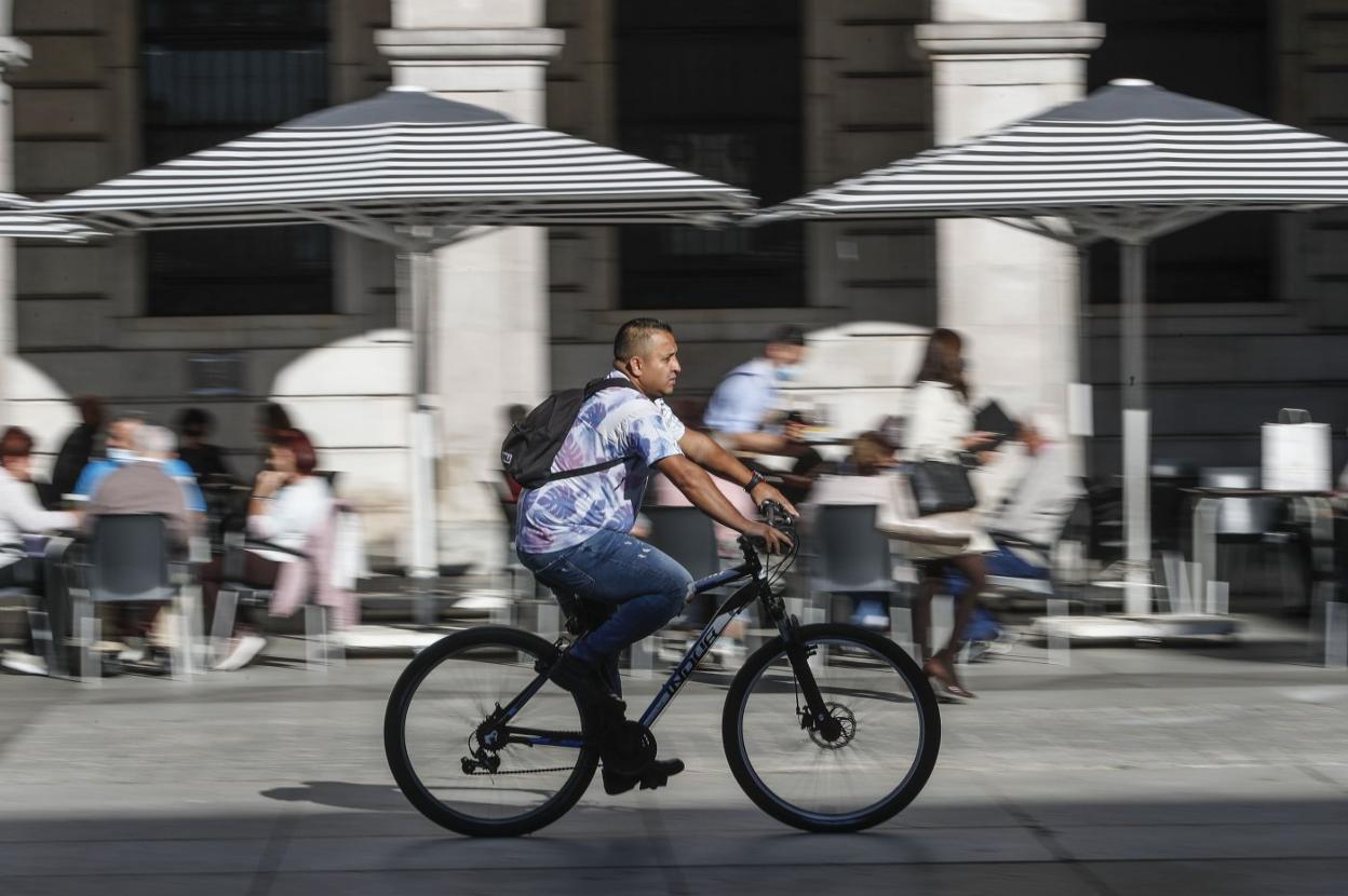 Un ciclista atraviesa la Plaza Porticada con su bicicleta. 