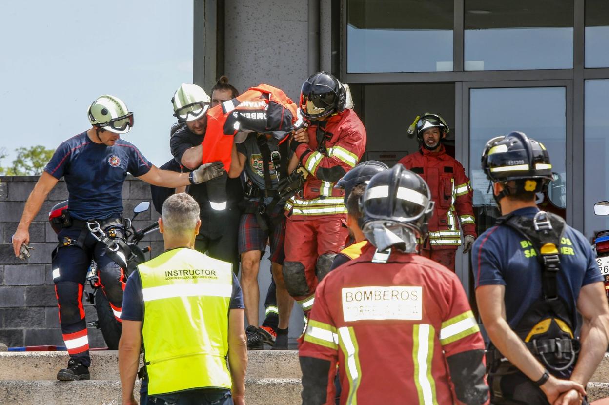 Efectivos de bomberos rescatan al sujeto, el jueves, durante la parte práctica del ciclo simulado en el parque de Torrelavega.