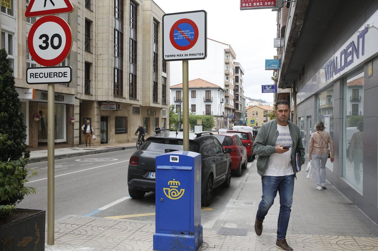 Un vecino circula junto a una zona de carga y descarga, las plazas donde se implantará el nuevo modelo de aparcamiento en Torrelavega. 