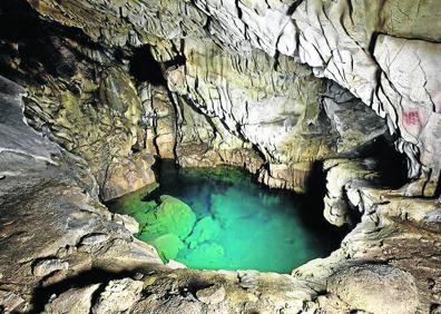 Imagen secundaria 1 - En algunos momentos se utilizó una barca para llegar a la cueva. Pozo dentro de la cavidad y valla que la protege.