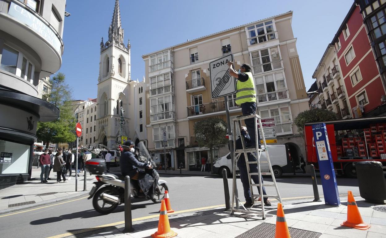 Dos operarios retiran el cartel de fin de zona 30 de la calle Rualasal para adaptar la señalización a los nuevos límites de velocidad. 