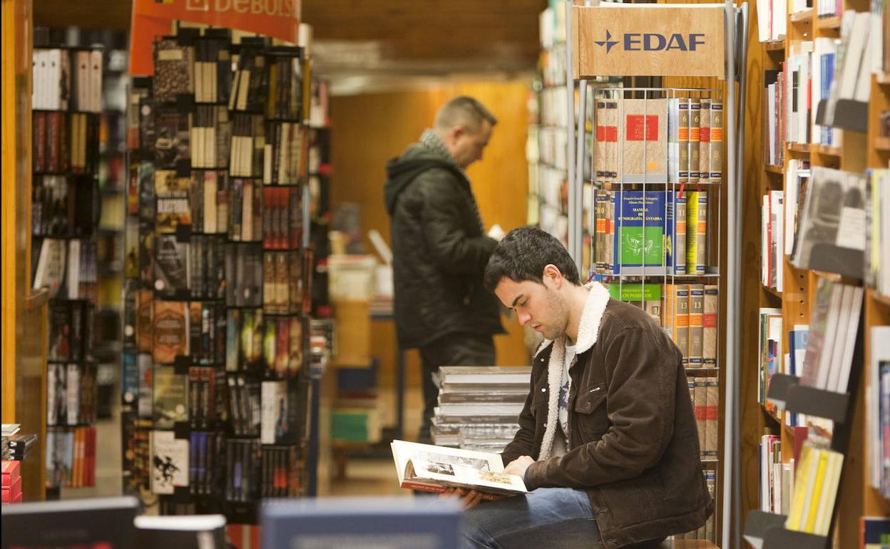 Un joven lee un libro en la librería Estudio de Santander. 