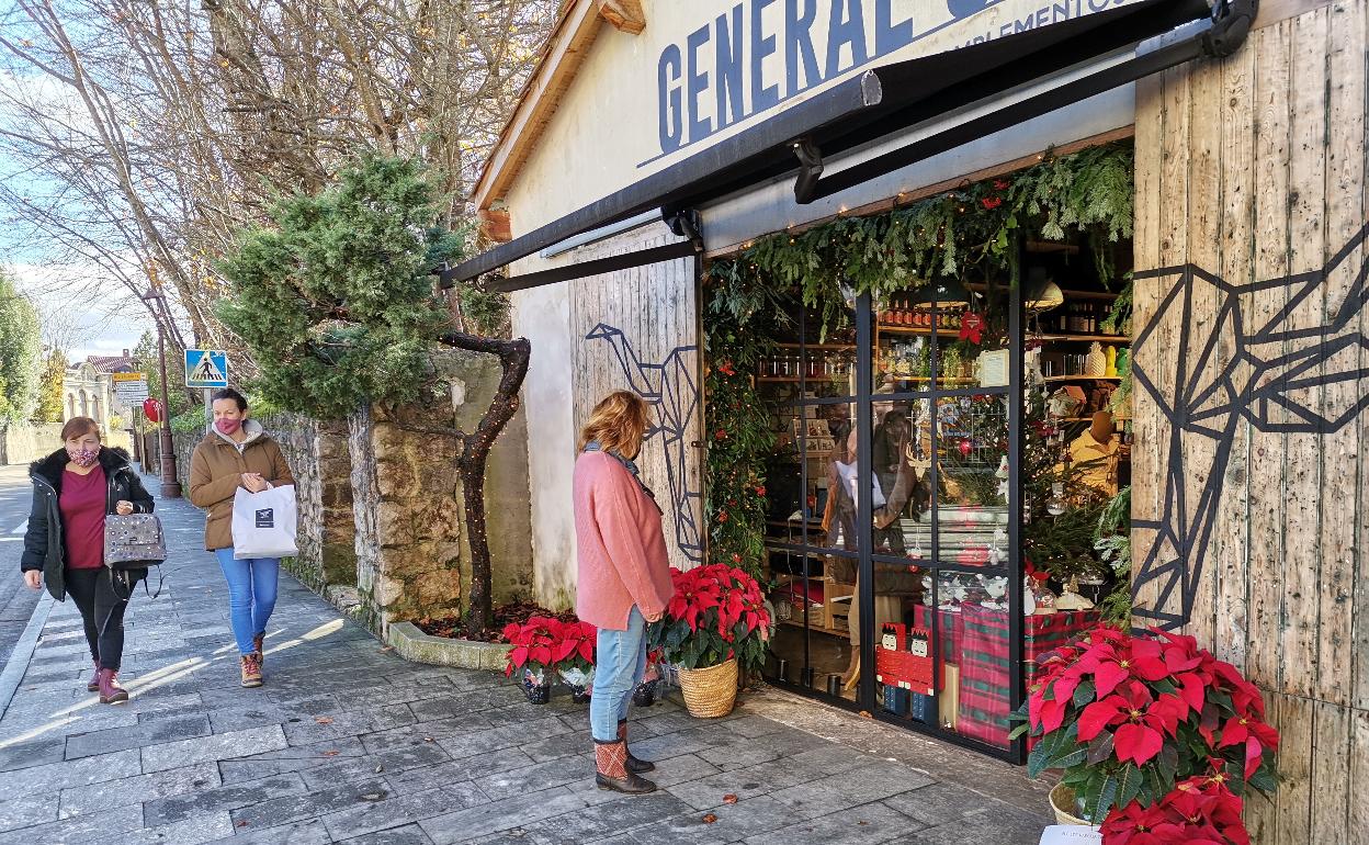 Una vecina observa el escaparate de una tienda en Comillas. 