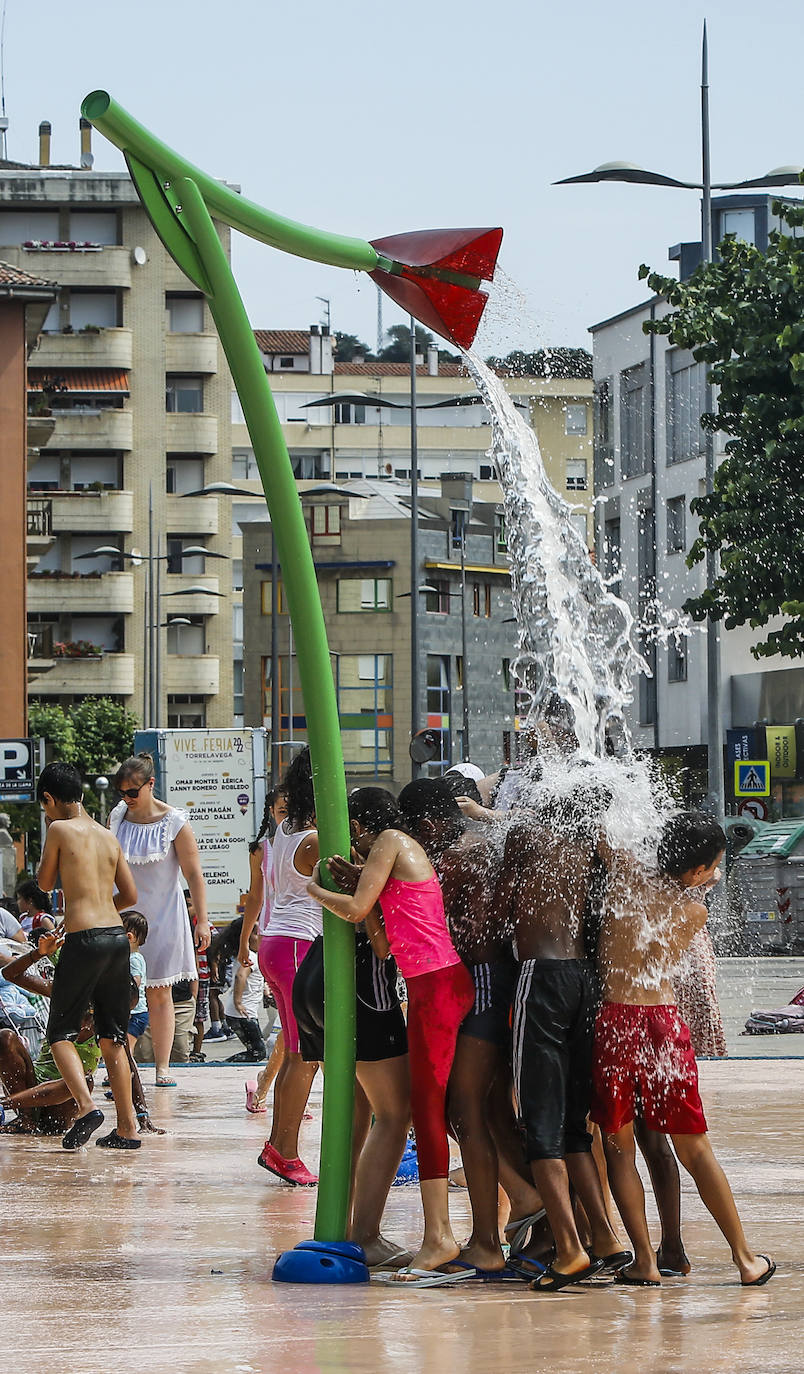 Un grupo de chavales, bajo un corro de agua en el parque del agua de Torrelavega.