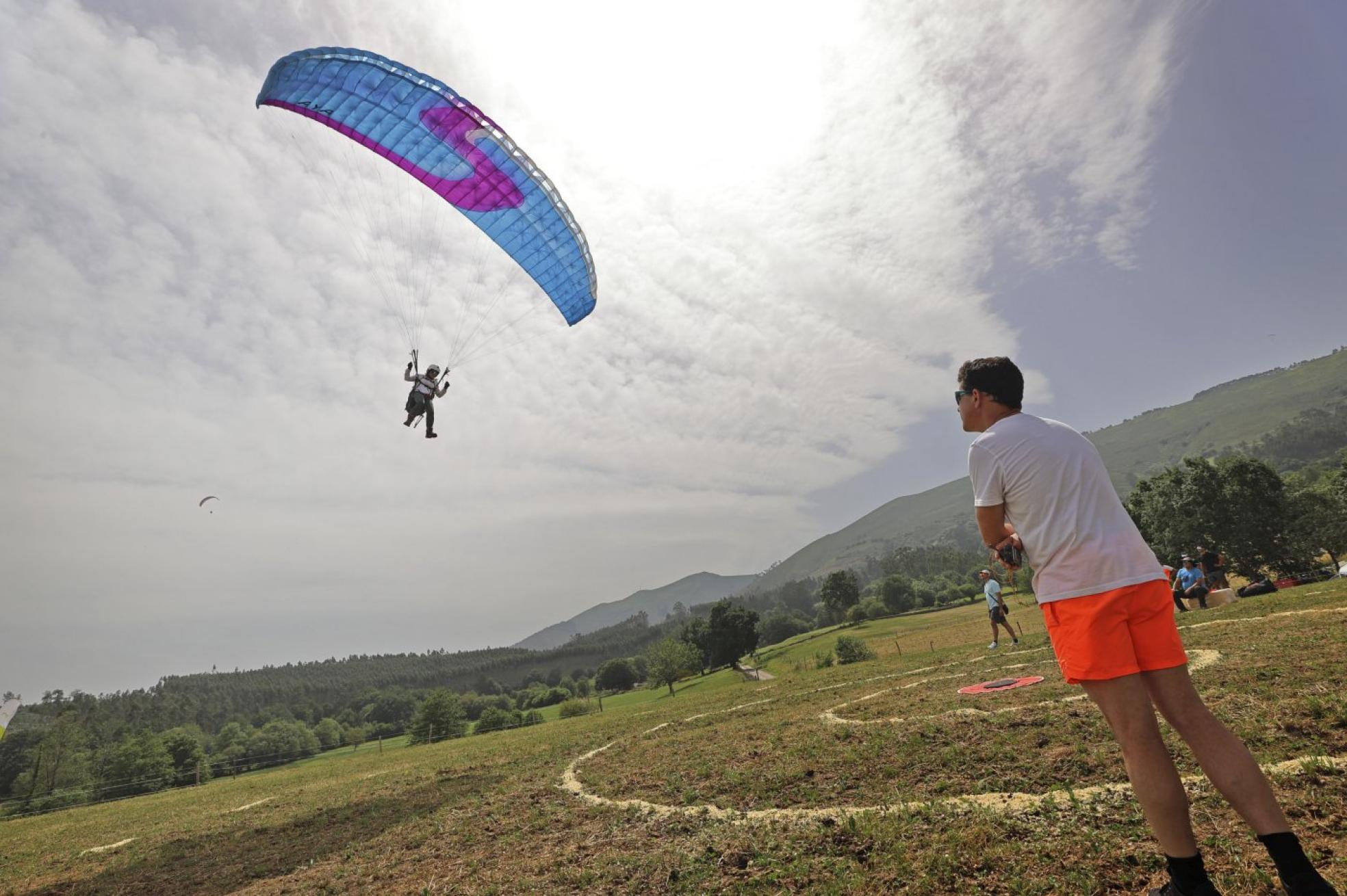 Uno de los participantes en la prueba de parapente de precisión se dispone a aterrizar en la mies de Mazcuerras. 