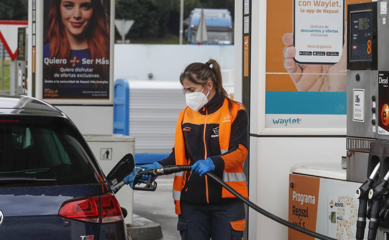 Una trabajadora pone combustible a un coche.