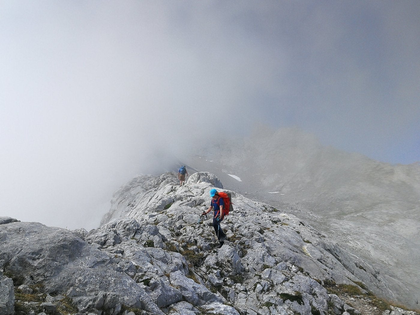 Dos montañeros, entre la niebla en la Corona del Raso. 