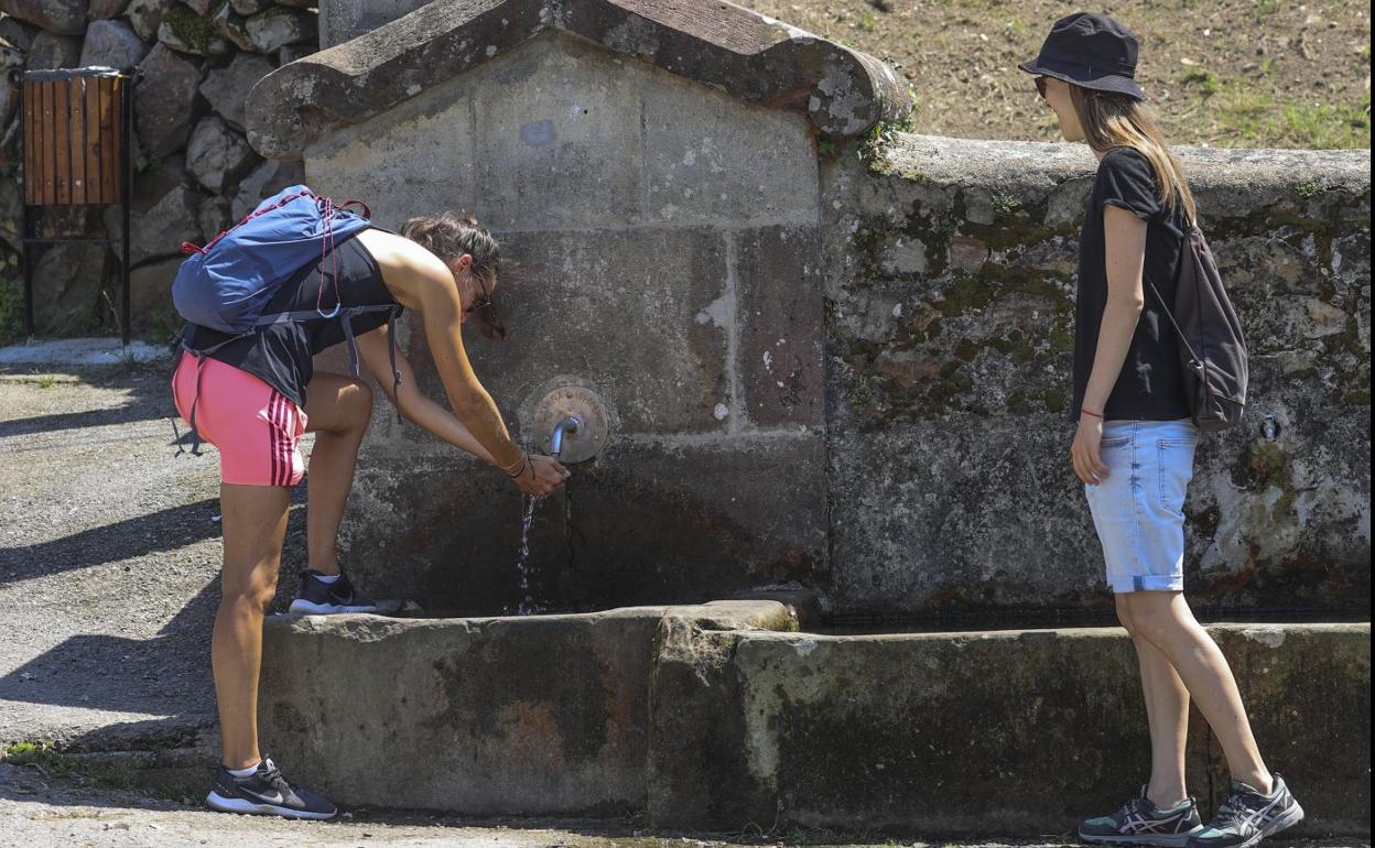 Dos mujeres se refrescan, ayer, en una fuente del pueblo de Lamiña. 