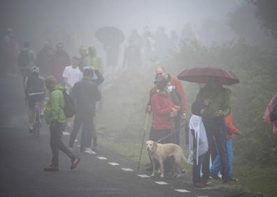 Imagen secundaria 1 - Un jinete por la carretera de Pico Jano, la niebla que marcó la jornada y paso del pelotón por el arco de La Cavada.