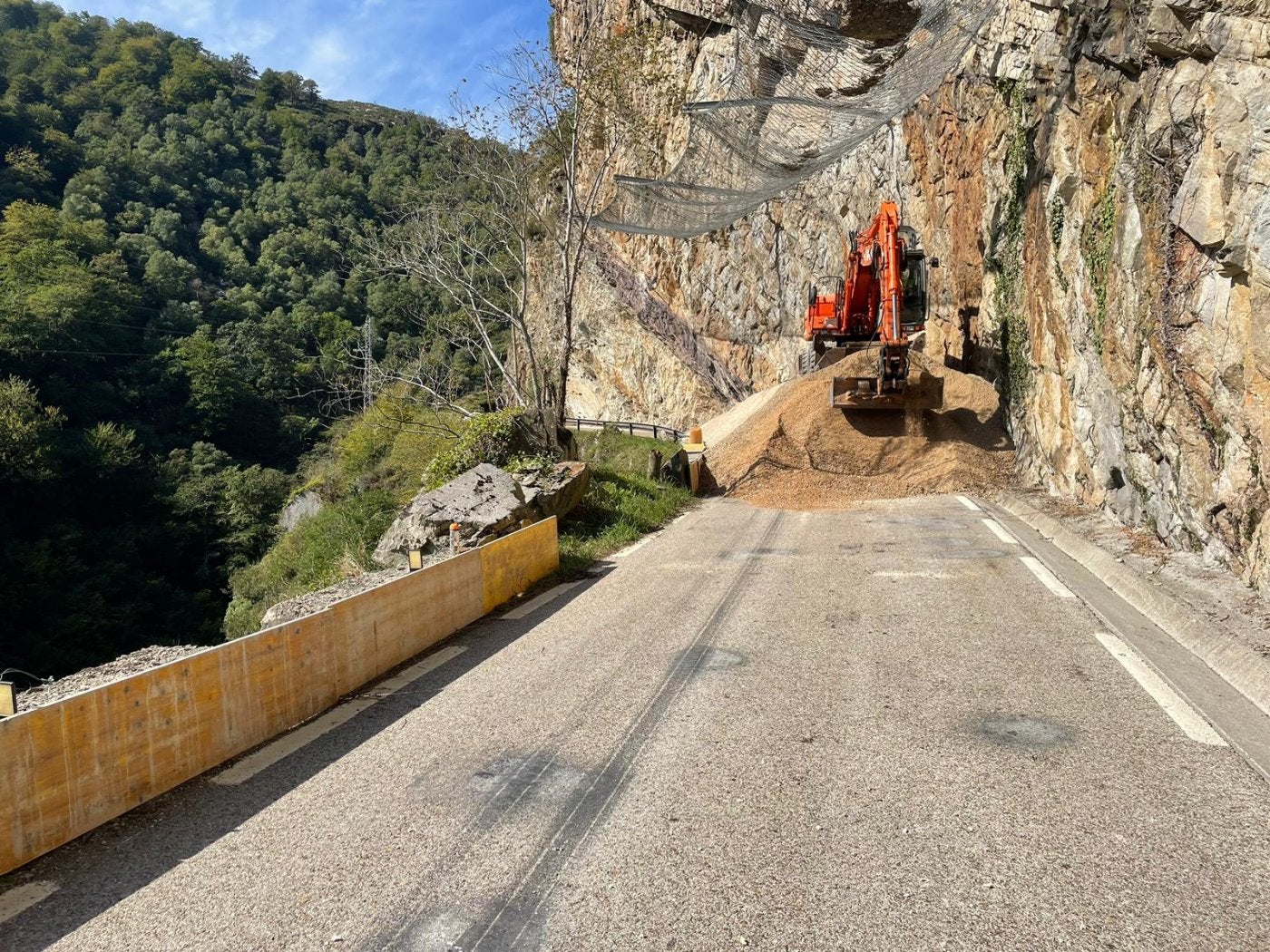 Una excavadora extiende una capa de zahorra en la zona en la que se realizarán los trabajos para evitar los desprendimientos de rocas. 