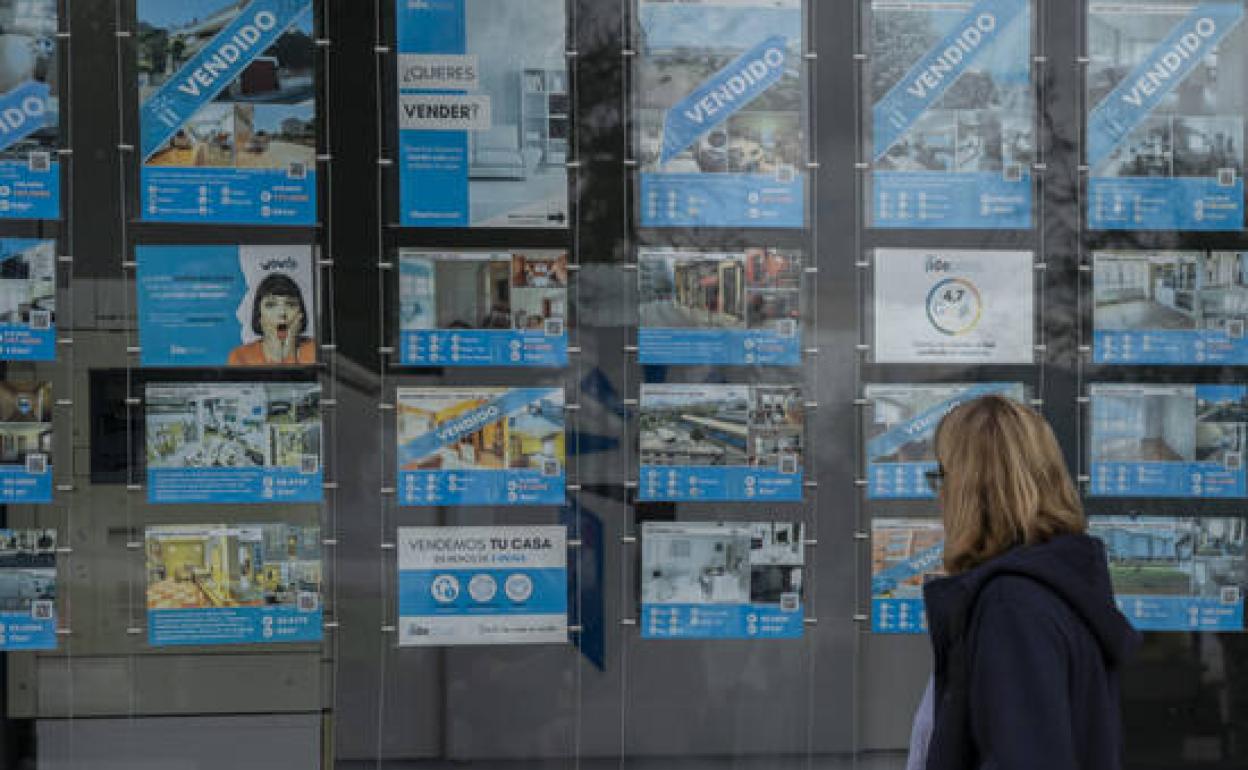 Una mujer mira un escaparate de una inmobiliaria. 