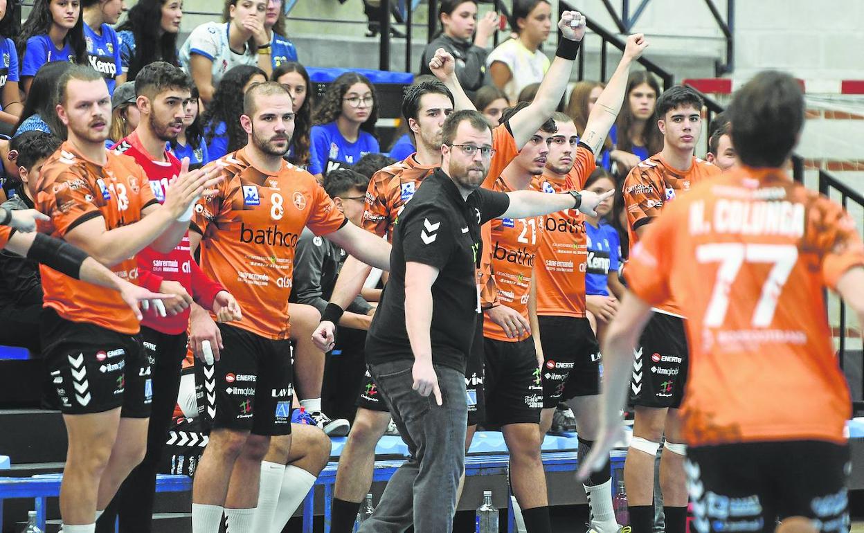 El banquillo del Bathco Torrelavega celebra un gol naranja mientras el técnico Álex Mozas da indicaciones a Nico Colunga desde la banda. 