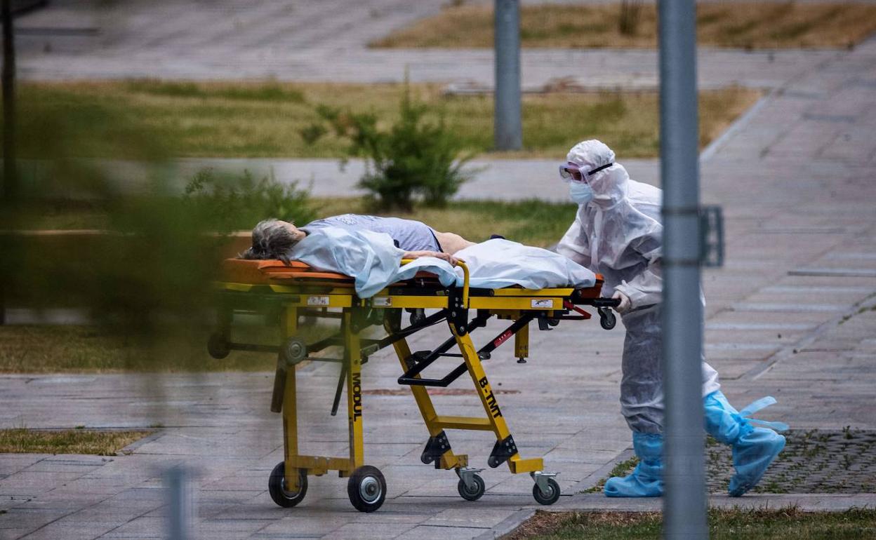 Un técnico sanitario lleva en camilla a una enferma de covid-19.