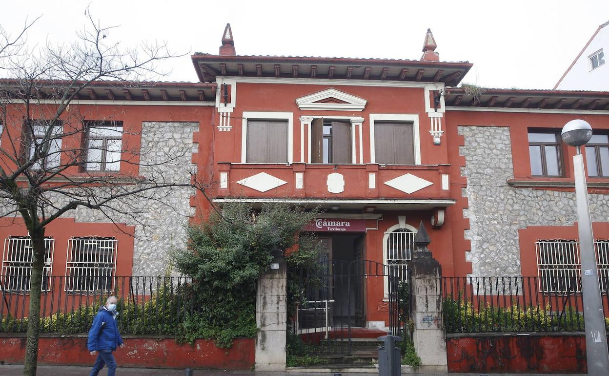 Vecinos pasan frente a la antigua sede de la Cámara de Comercio, en Torrelavega.