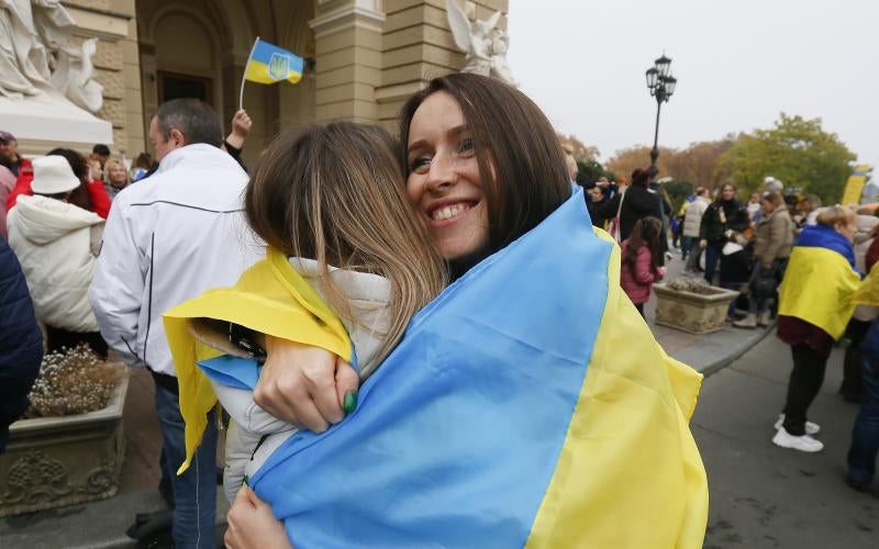 Dos jóvenes se abrazan envueltas en la bandera de Ucrania tras la entrada de las tropas en Jersón