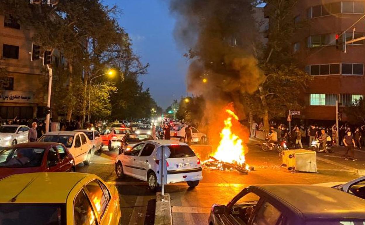 Un grupo de manifestantes prenden fuego a una moto de la Policía durante una jornada de protestas en Teherán. 