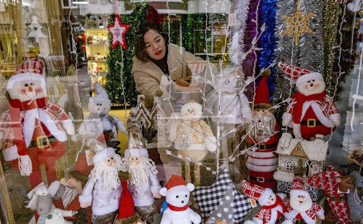 Una dependienta coloca el escaparate navideño en Sarón. 