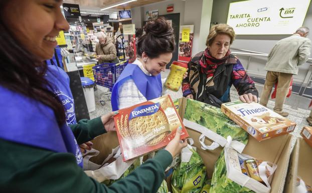 Las voluntarias, con peto azul, recogen y clasifican las donaciones de alimentos.