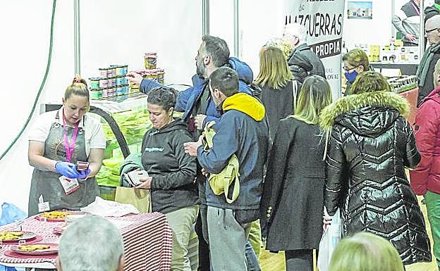 Unos clientes preguntan sobre los productos en un puesto. 