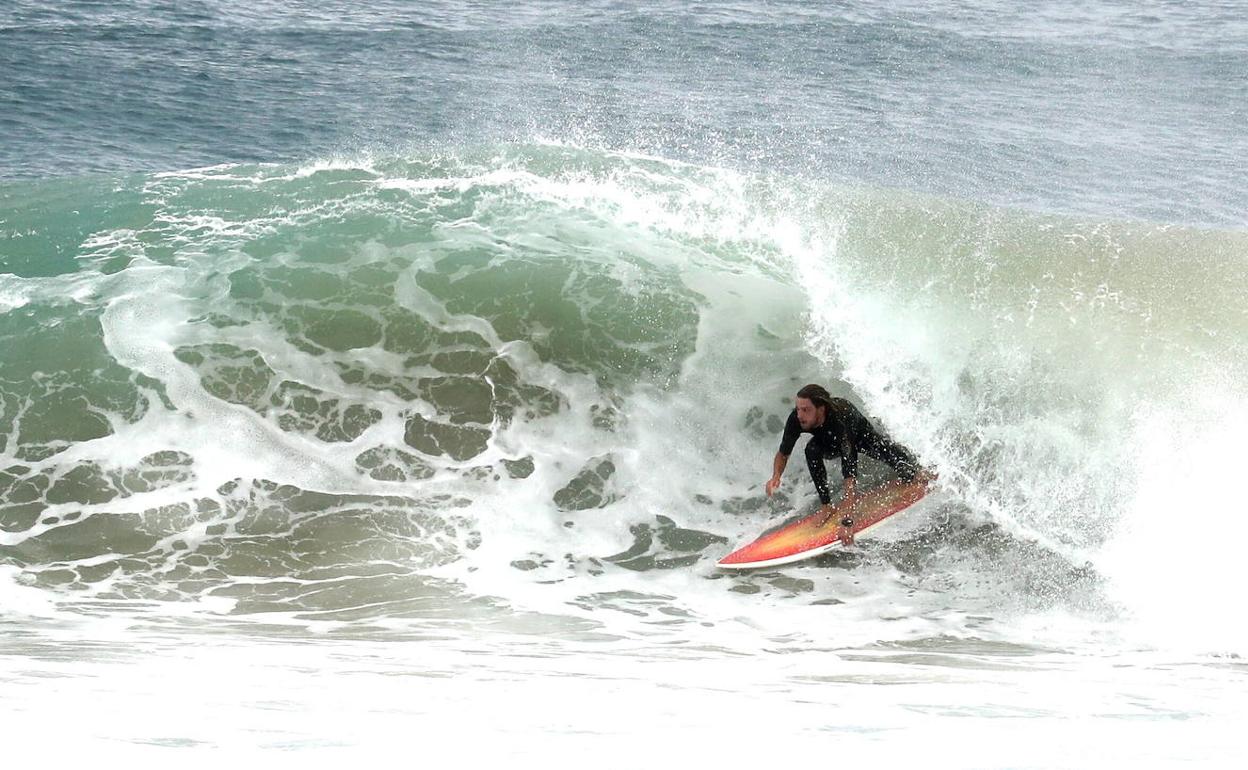 Un joven practica surf en un día de oleaje. 