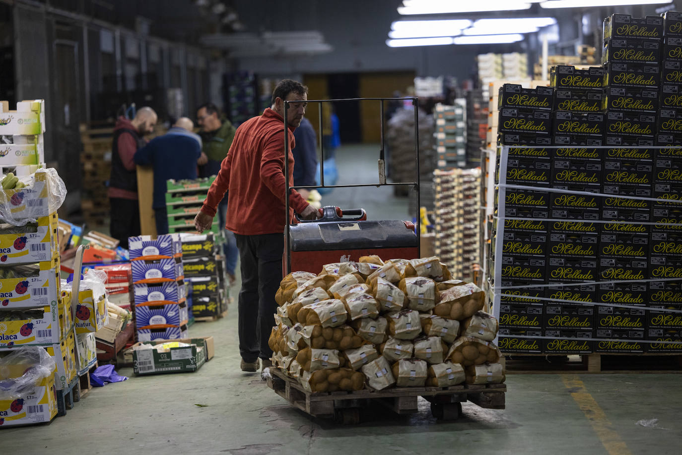 Un empleado empuja un carro con sacos de patatas