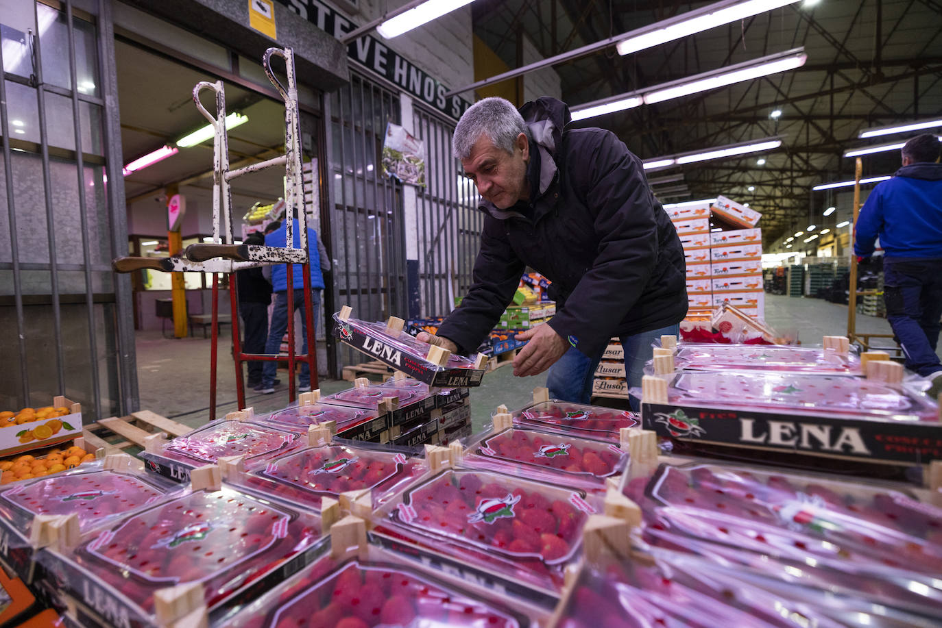 Un cliente echa un vistazo a una caja de fresas. 